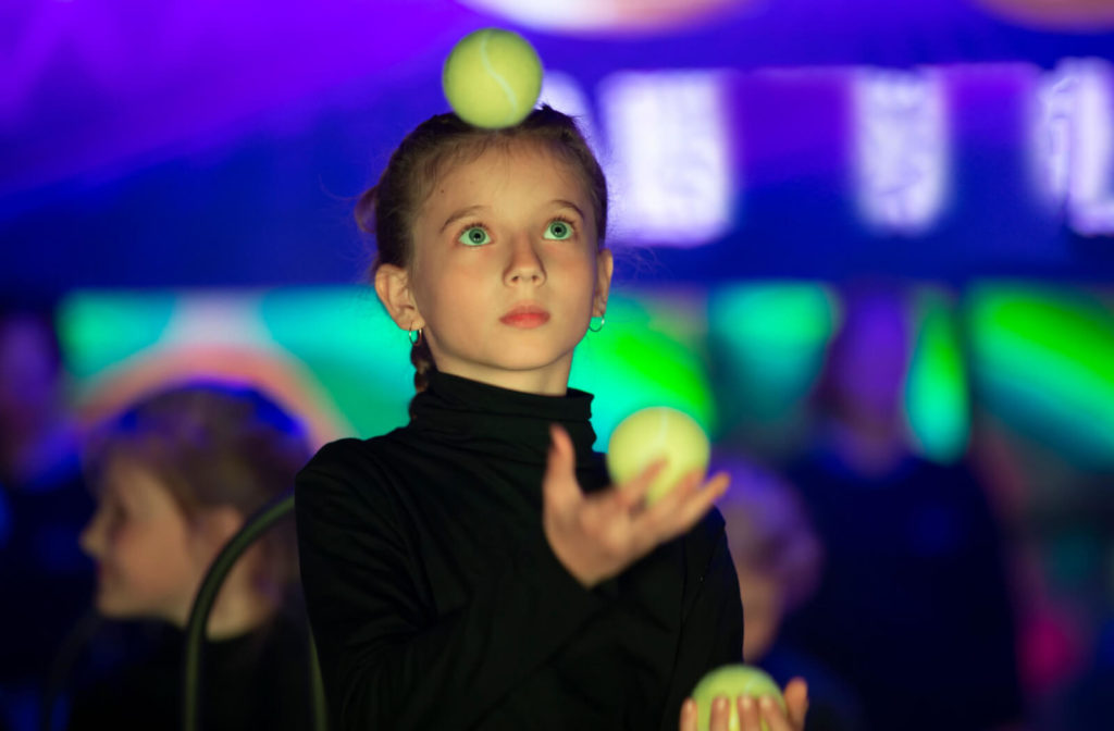 A young girl is juggling balls. Juggling can improve your hans-eye coordination.