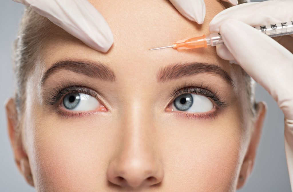 Young woman receiving a cosmetic injection of Botox in her forehead.
