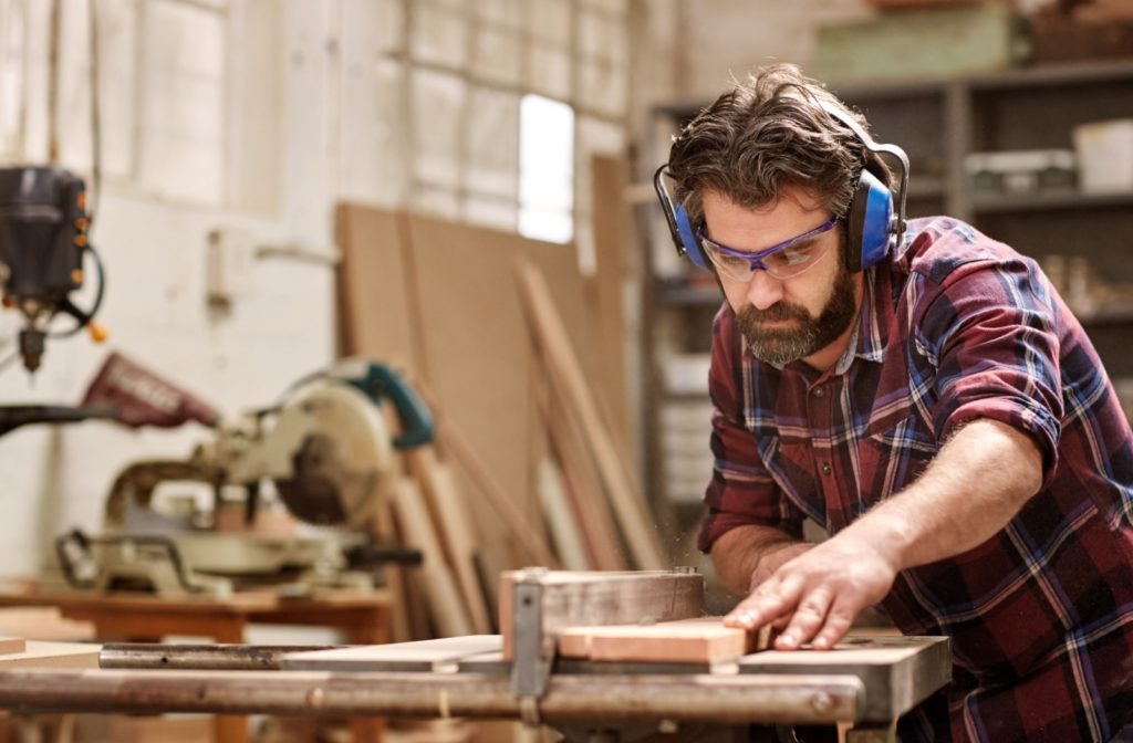 A carpenter wearing safety goggles while they work to protect their eyes from injury