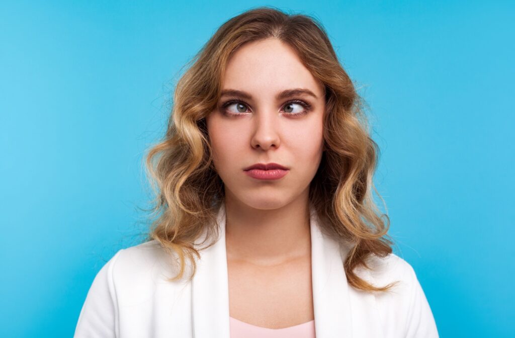 Person with blonde hair crossing their eyes against a blue background.
