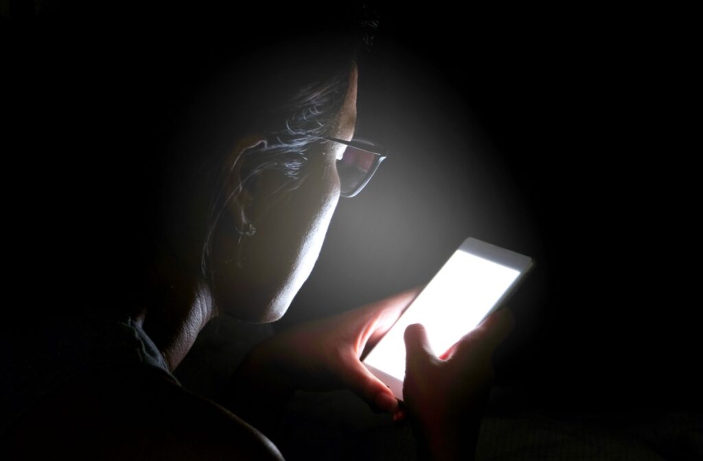 A person staring at a bright phone screen in a dark room
