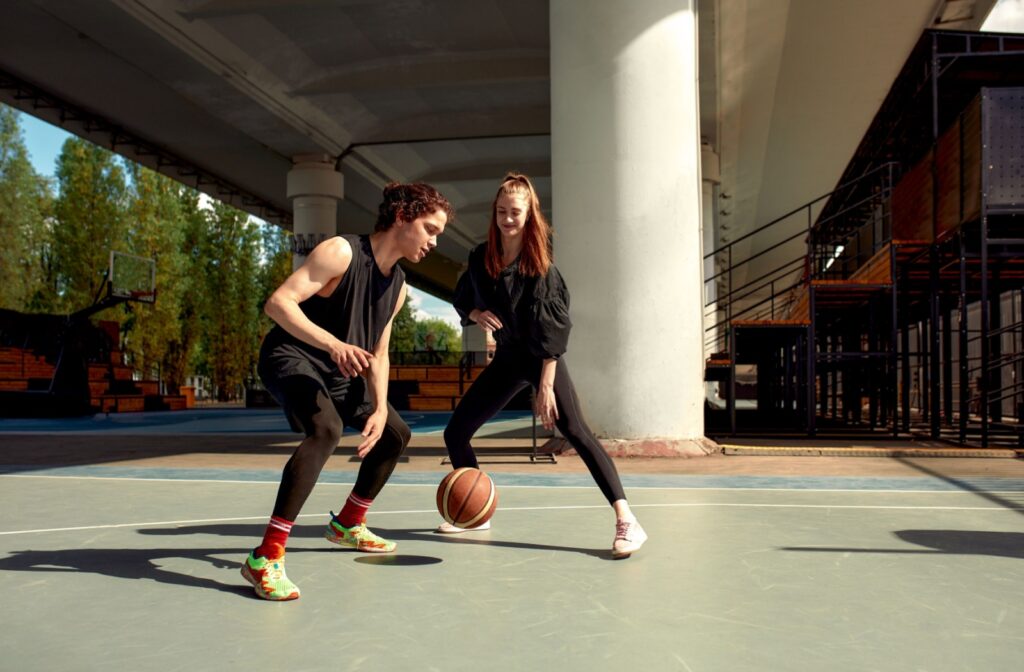 Two people playing basketball outside.